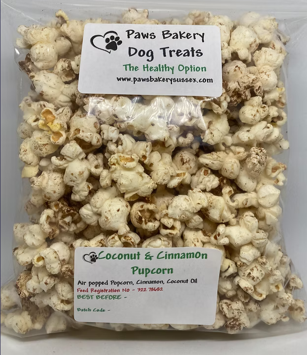 Bag of coconut and cinnamon popcorn with Paws Bakery Dog Treats label on a white background