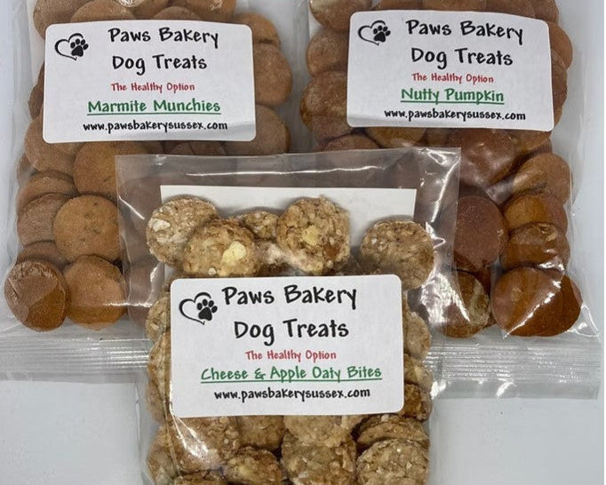 Three packages of Paws Bakery dog treats on a white background